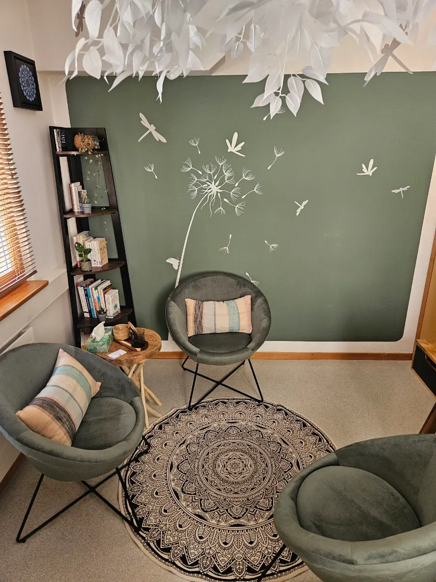Trois fauteuils autour d’un tapis mandala, devant le mur vert du cabinet.