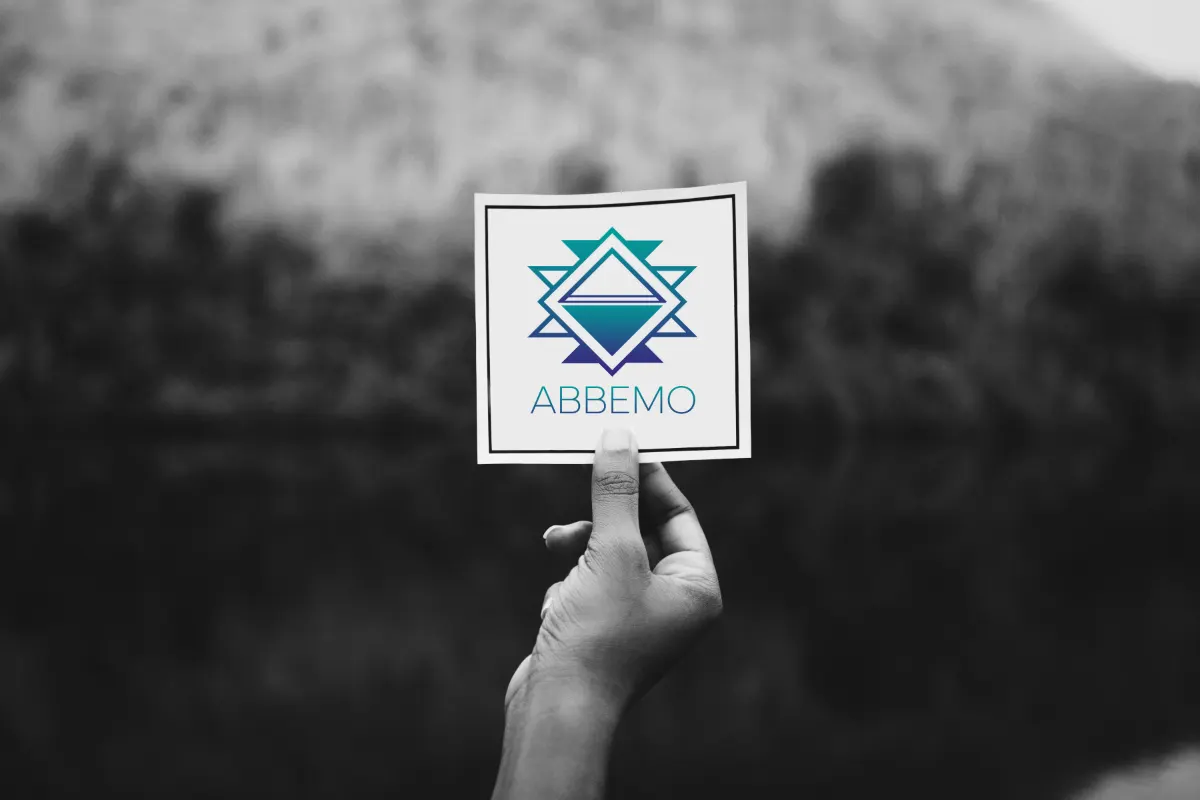 Une main tient une carte Abbemo devant un paysage flou.